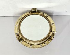 a porthole mirror mounted on the side of a wall with rivets and screws