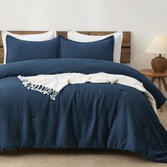 a bed with blue comforter and white pillows