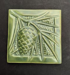 a ceramic tile with an image of a pine cone on it's center piece