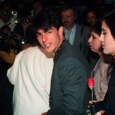 a man in a suit and tie is surrounded by people with cameras taking pictures at an event