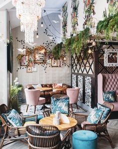 a room filled with lots of furniture and plants hanging from the ceiling over it's windows