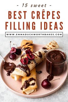 crepes filled with chocolate and cherries on a pink plate next to a jar of dipping sauce