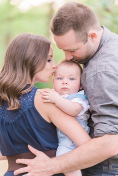 a man and woman holding a baby in their arms