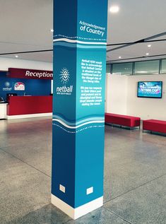 an airport lobby with blue and white signage on the wall, red benches in the background