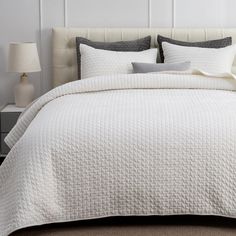 the bed is made with white quilts and pillows