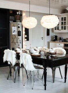 a black table with white chairs and lights hanging from it's ceiling in a kitchen