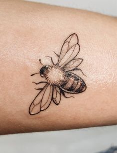 a small tattoo of a bee on the left arm, with an insect in it's center