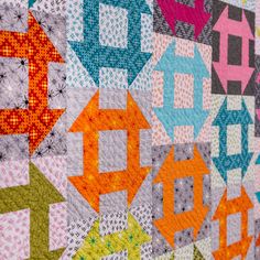 a close up of a quilt with many different colors and shapes on the wall behind it