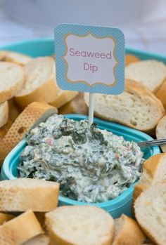 a blue bowl filled with dip surrounded by crackers on a white table cloth and a sign that says seaweed dip