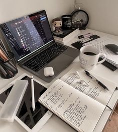 an open laptop computer sitting on top of a desk next to a cup of coffee