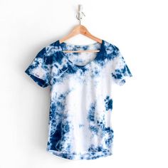 a blue and white t - shirt hanging on a hanger against a white wall