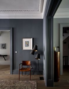 an empty room with a chair, lamp and pictures hanging on the wall in it