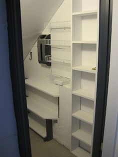 an open door leading to a room with white shelves and shelving units in it