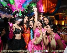 a group of women dressed in colorful costumes posing for a photo with their arms in the air