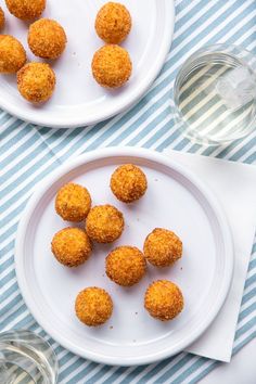 two white plates with small bites of food on them next to a glass of water