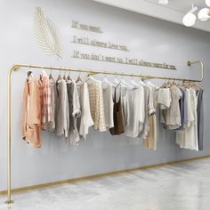 a clothing rack with clothes hanging on it in front of a wall that says,