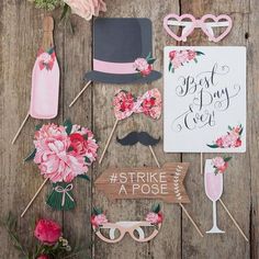 wedding photo booth props on wooden planks with pink flowers and wineglasses in the background