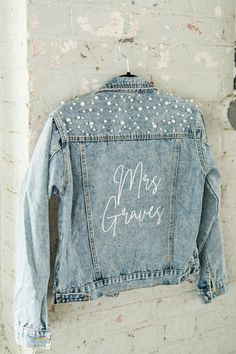 a denim jacket with the words miss glamis written on it hanging from a brick wall