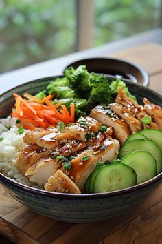 a bowl filled with rice, cucumbers and chicken