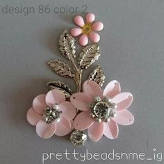 a pink flower brooch sitting on top of a white table next to a gray wall