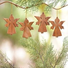 three wooden angel ornaments hanging from a tree branch