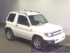 a white suv is parked in a parking lot next to a wall and some windows