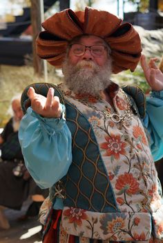 a man with a long beard wearing an orange hat and blue shirt is making the peace sign