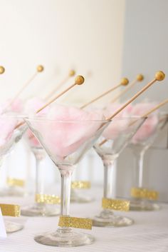 pink and gold desserts in martini glasses on a white tablecloth with gold pins