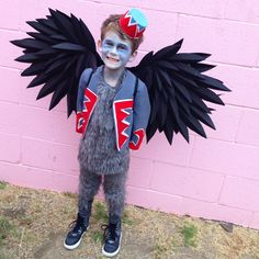 a young boy dressed up as a bird with blue paint on his face and wings