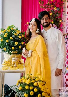 a man and woman standing next to each other in front of flowers on a table