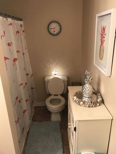 a bathroom with a toilet, vanity and shower curtain in the corner is decorated with pink flamingos