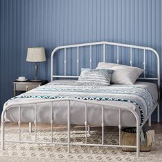 a white metal bed in a bedroom with blue walls and rugs on the floor