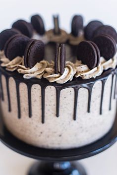 an oreo cookies and cream cake is on a black stand with white frosting