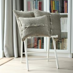 two pillows on a chair in front of a bookshelf