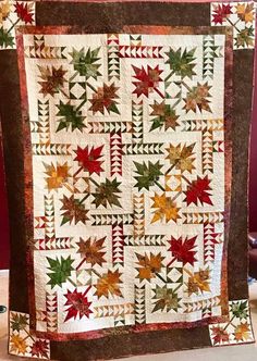 a quilted wall hanging with autumn leaves on it