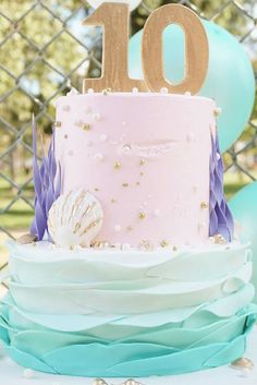 a pink and blue cake sitting on top of a table next to a number 10 sign