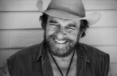 a black and white photo of a man wearing a cowboy hat with his eyes closed