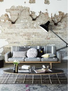 a living room with a couch, coffee table and lamp on the wall behind it