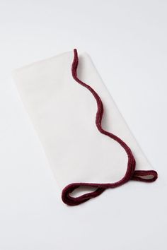 a piece of cloth with a red thread on it sitting on top of a white surface