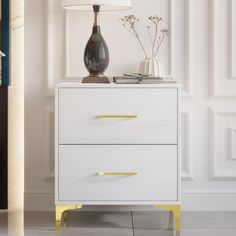 a white dresser with two drawers and a lamp on top