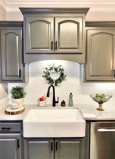 a kitchen with gray cabinets and white counter tops, including a farmhouse sink in the center