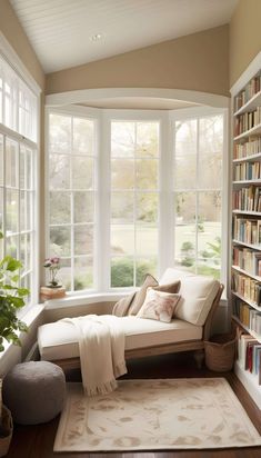 a living room filled with lots of books and furniture next to a large open window