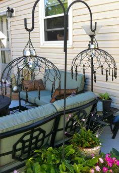 outdoor furniture is sitting on the back porch in front of a house with flowers and potted plants