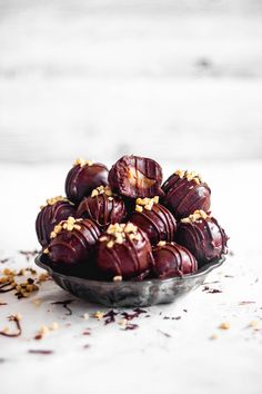 a bowl filled with chocolate covered donuts on top of a white tablecloth and sprinkled with nuts