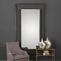 a mirror sitting on top of a wooden table next to a chair and vases