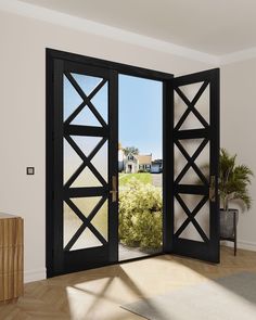 an open black door leading to a beautiful house in the distance, with a view of a field through it