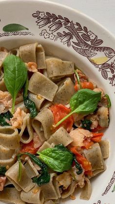 a white plate topped with pasta and spinach