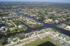 an aerial view of a river running through a city with houses in the water and trees on both sides