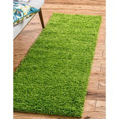 a green rug in the middle of a room with wooden floors and a bench on one side