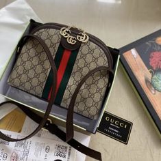 a gucci handbag sitting on top of a table next to a book and sunglasses